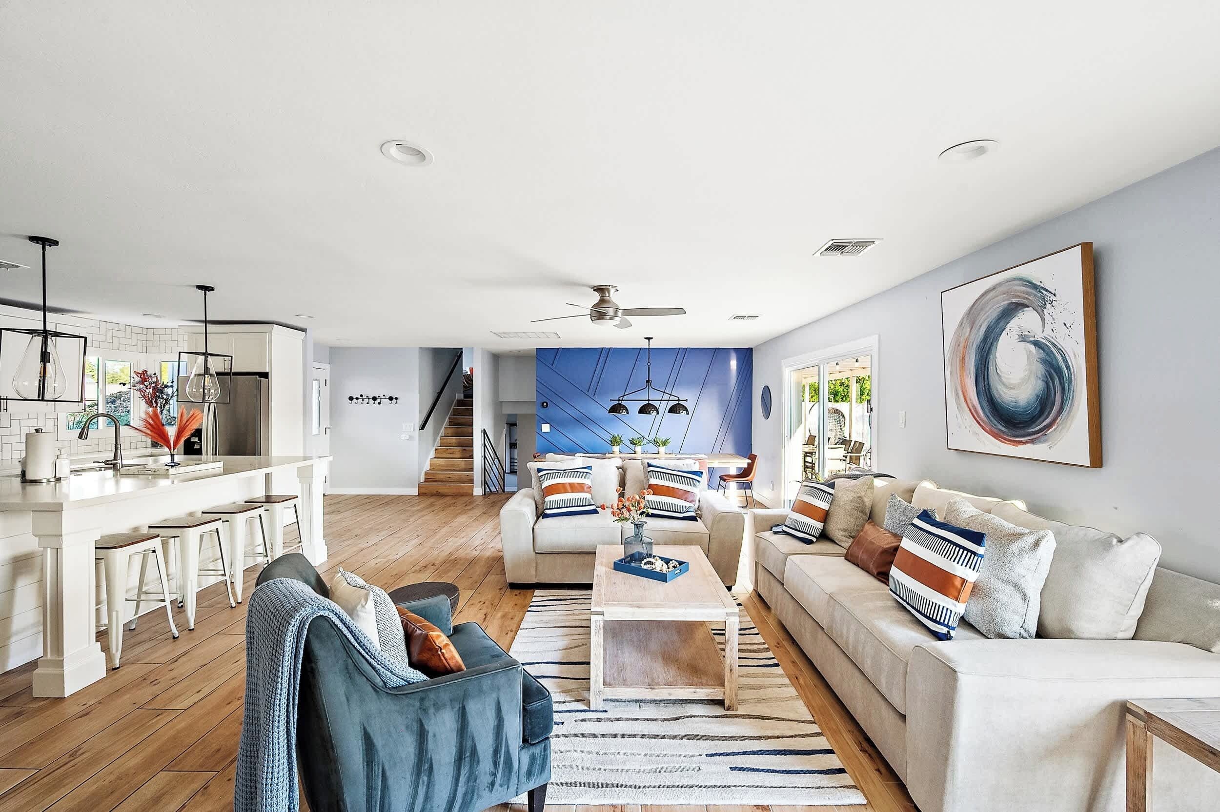 A modern living room with a sofa, coffee table, and a kitchen area with a white countertop and bar stools.