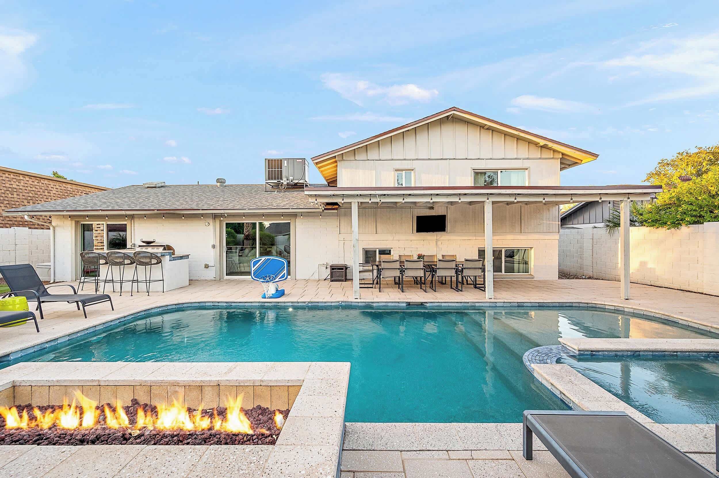Une maison moderne dotée d’une piscine, d’un espace salon extérieur et d’un foyer.