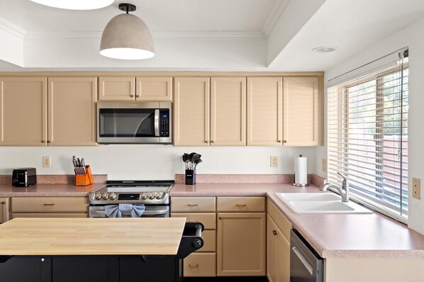 Une cuisine moderne avec des meubles de couleur beige, un four à micro-ondes, une cuisinière et un évier.