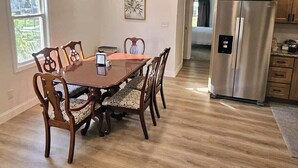 Un comedor con mesa y sillas de madera, un refrigerador de acero inoxidable y armarios de madera.
