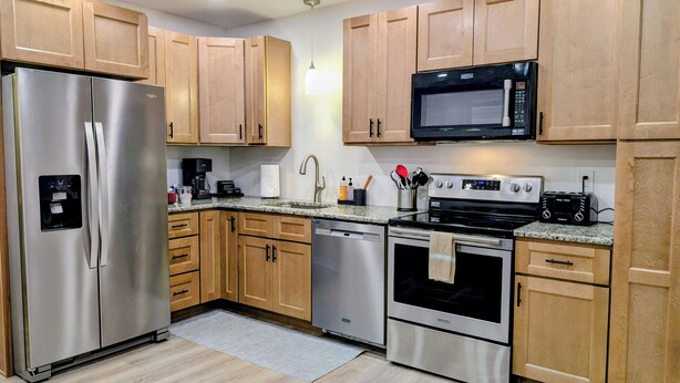 Una cocina moderna con electrodomésticos de acero inoxidable, gabinetes de madera y encimeras de granito.