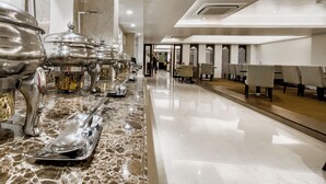 Um corredor longo com várias estações de buffet de um lado e uma área de estar do outro.