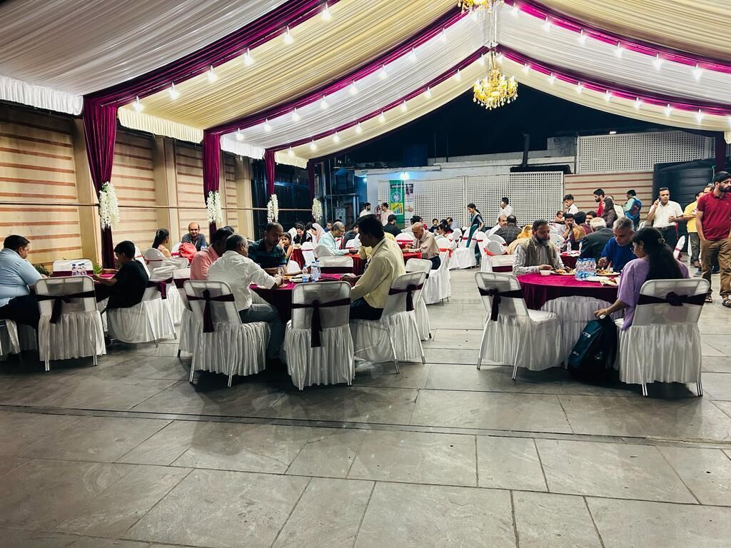 Un salón de banquetes con mesas redondas cubiertas con manteles blancos y sillas con cintas negras.