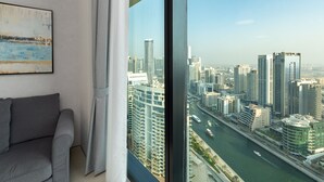 Una sala de estar moderna con un ventanal grande que ofrece vistas a un paisaje urbano y un río.
