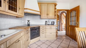 A kitchen with wooden cabinets, a built-in oven, a sink, and a coffee maker.