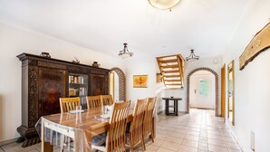 A dining area with a wooden table and chairs, a dark wooden cabinet, and a tiled floor.
