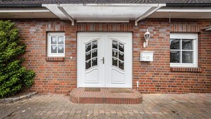 A brick building with a white double door, a small window, and a light fixture above the door.