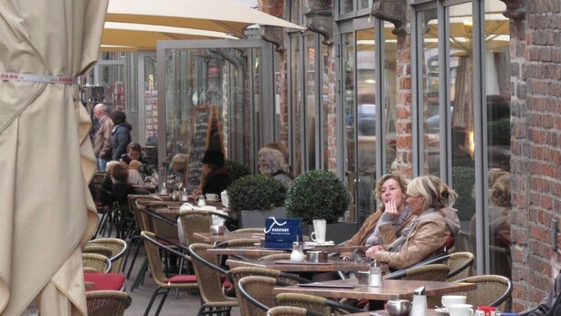 An outdoor café with brick architecture, tables, chairs, and umbrellas.