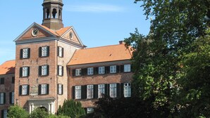 A large brick building with a clock tower, multiple windows, and a central entrance.