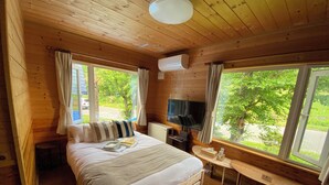 A wooden cabin room with a bed, TV, and a small desk. - Biei san-ai-no-oka Villa Shion (Biei)