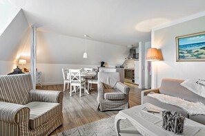 Un salon moderne avec des canapés à rayures, un coin repas et une cuisine en arrière-plan.