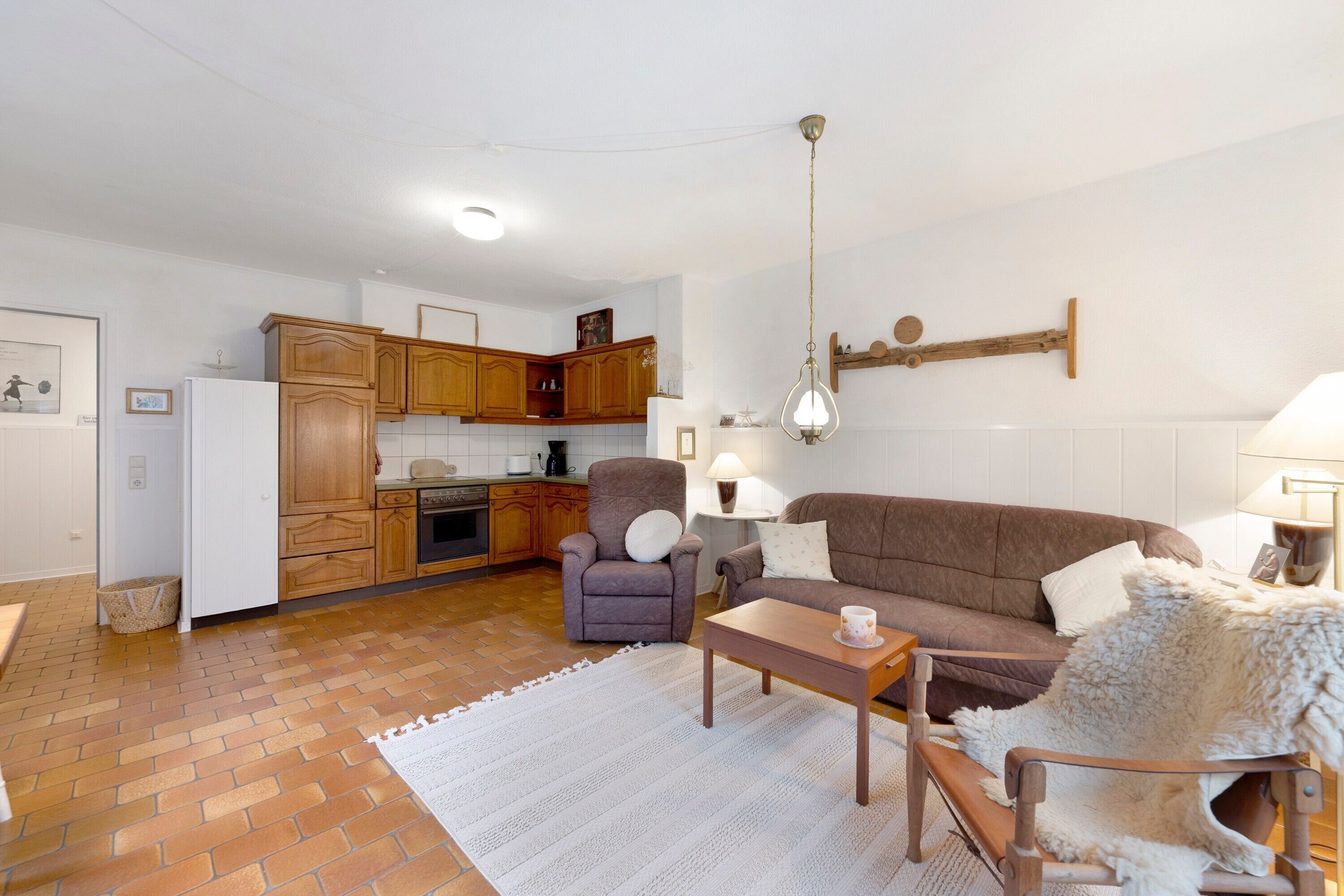 Een woonkamer met een bank, fauteuil, salontafel en vloerkleed.