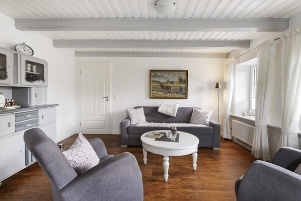 A living room with a grey sofa, a white coffee table, and a painting on the wall.