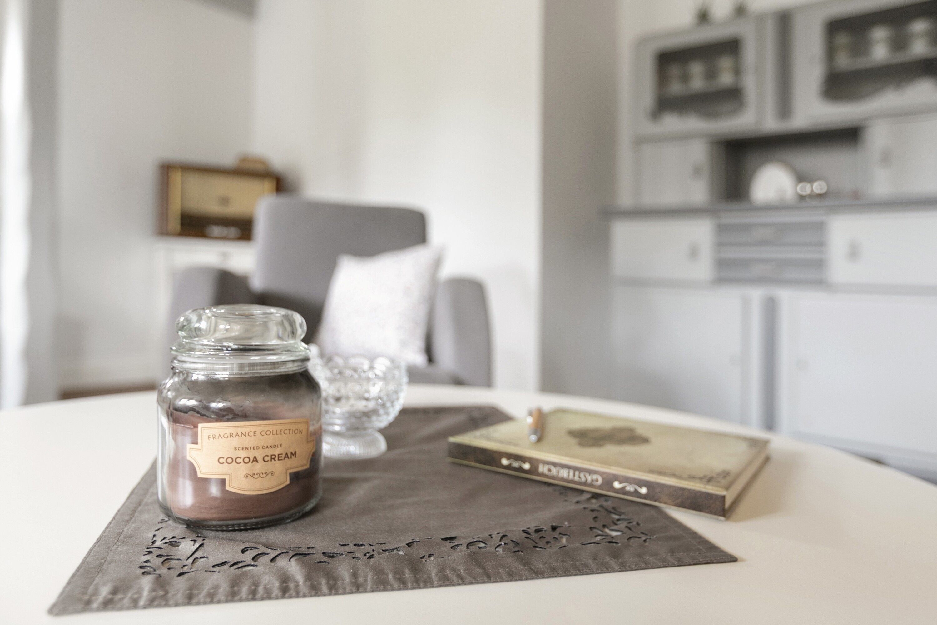 Une pièce dans laquelle se trouve une table sur laquelle sont disposés un bougeoir parfumé, un livre et un vase décoratif.