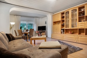 A living room with a sofa, a coffee table, a TV, and wooden cabinets. - Apartment 'Rosi's Ferienwohnung' with Private Garden and Wi-Fi (Hohenzieritz)