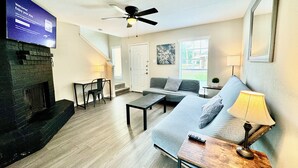 A living room with a fireplace, a sofa, a coffee table, and a TV mounted on the wall.