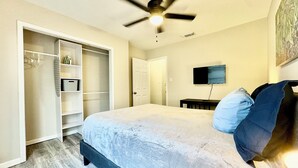 A bedroom with a bed, a ceiling fan, a TV, and a closet.