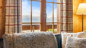 A cozy room with a large window offering a mountain view, wooden walls, and a plush sofa. - Eole - 6 pers - près des pistes (Haute-Nendaz)