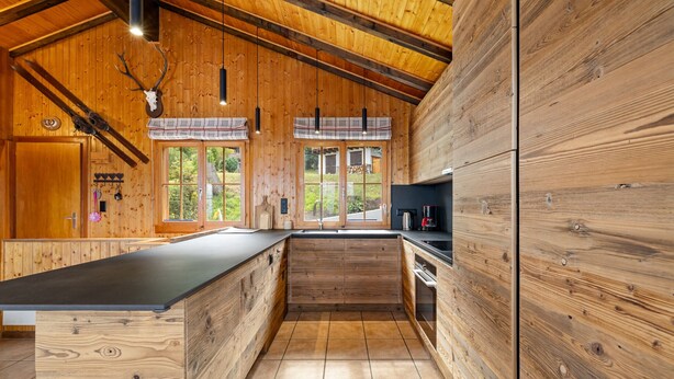 A wooden cabin kitchen with a long counter, wooden walls, and a window overlooking greenery. - Eole - 6 pers - près des pistes (Haute-Nendaz)