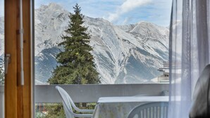 A balcony with a view of snow-capped mountains, a pine tree, and a glimpse of a building below. - Les Hauts-de-Nendaz A A0 - 5 pers - ski In&Out (Haute-Nendaz)
