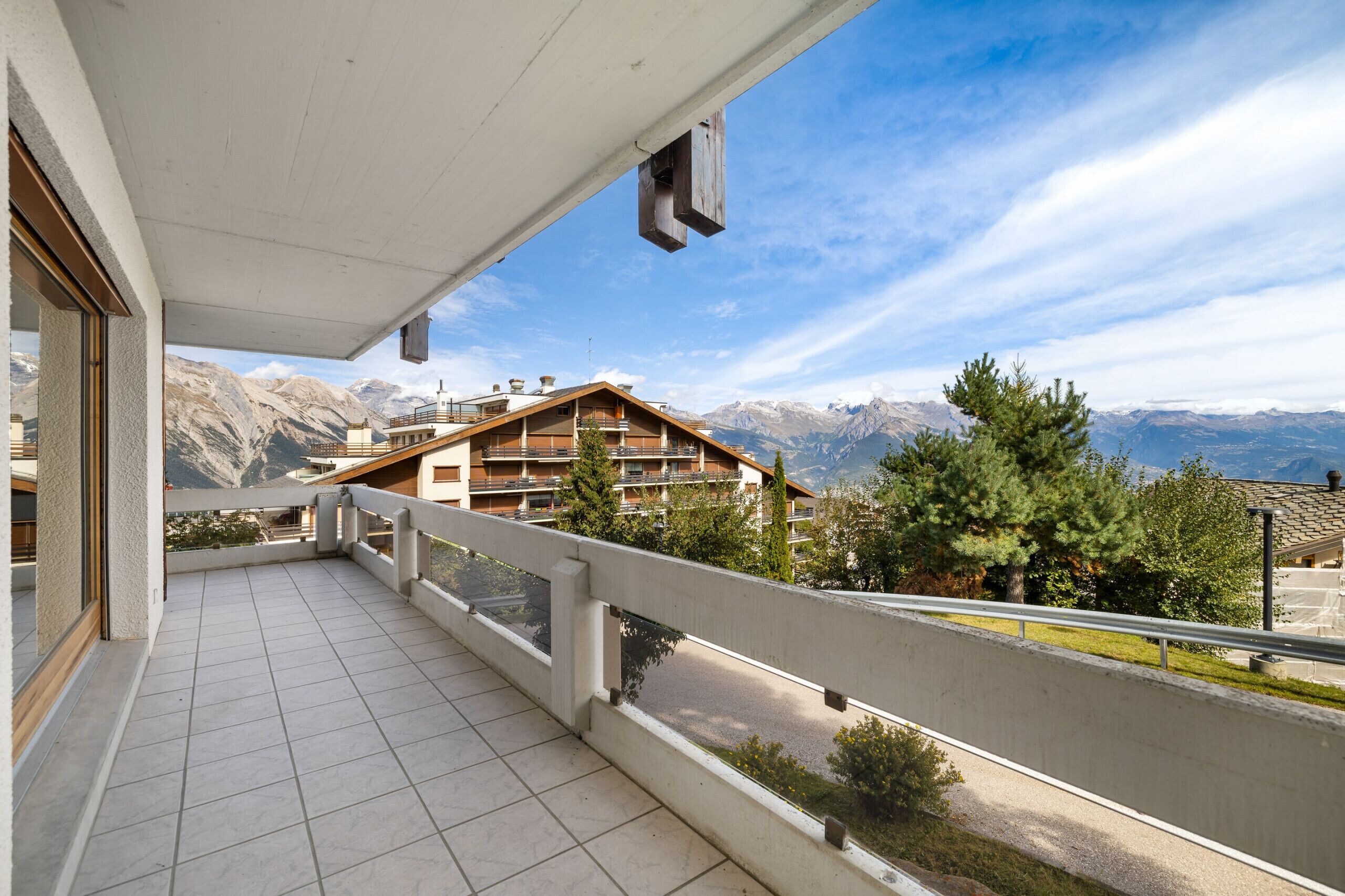 Un balcon avec vue sur les montagnes et un bâtiment en arrière-plan.