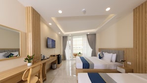 A hotel room with a wooden desk, a bed, a TV, and a view of the outside. - Ben Thanh Luxury Suite Hotel & Spa (Ho Chi Minh City)