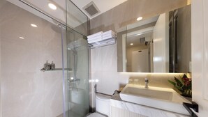 A modern bathroom with a glass shower enclosure, a white toilet, and a vanity with a sink and mirror. - Ben Thanh Luxury Suite Hotel & Spa (Ho Chi Minh City)