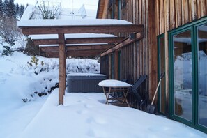 Un edificio in legno con una veranda coperta, una vasca idromassaggio e una pala.