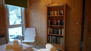A room with a wooden bookshelf, a white chair, and a bed with rolled towels. - Dreamy chalet on the slopes (Sankt Georgen am Kresichberg)