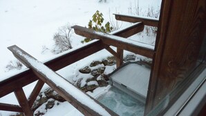 A wooden deck with snow accumulation, a glass door, and a view of a snowy landscape with sparse vegetation. - Dreamy chalet on the slopes (Sankt Georgen am Kresichberg)