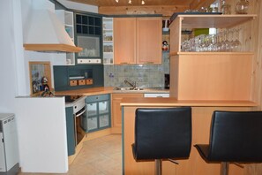 Una cucina compatta con mobili in legno, forno integrato e un piccolo angolo ristoro con due sedie.