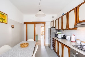 Una cocina compacta con comedor, armarios de madera, estufa a gas y una lámpara colgante.