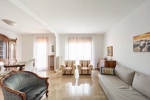 Amplia sala de estar con sofá, sillones, una mesa de comedor y un aparador.