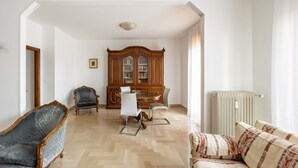 Ein Zimmer mit Esstisch, Stühlen, einem Schrank, einer Heizung und einem Sofa.