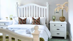 A white bed with patterned pillows, a white nightstand with drawers, and a vase with dried plants on the nightstand. - Perfectly Coastal, Quiet Central Retreat mins to Town Centre, Beach, Pier, Old Town & Train Station (Hastings)