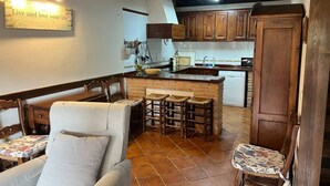 A kitchen with wooden cabinets, a bar area, and a dining set. - 15A08 El Rosal (Llanes)
