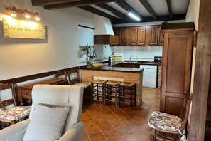 A kitchen with wooden cabinets, a bar area, and a dining set. - 15A08 El Rosal (Llanes)