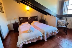 A bedroom with two beds, a wooden headboard, bedside lamps, a chair, and a window.