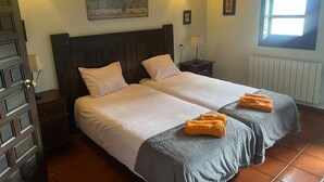 A double bed with two pillows, a nightstand, a lamp, a painting on the wall, and a window with natural light. - 15A08 El Rosal (Llanes)