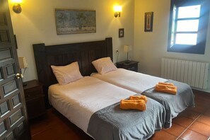 A double bed with two pillows, a nightstand, a lamp, a painting on the wall, and a window with natural light. - 15A08 El Rosal (Llanes)