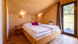 A wooden cabin bedroom with two beds, a nightstand, and a window with a view of the outdoors. - Spacious chalet with sauna (Sankt Georgen am Kresichberg)