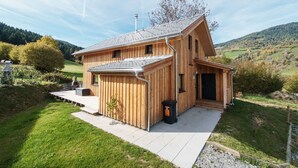 A wooden cabin with a sloped roof, a small porch, and a view of a green valley. - Spacious chalet with sauna (Sankt Georgen am Kresichberg)