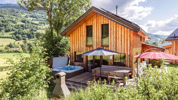 A wooden cabin with a hot tub, outdoor seating, and a scenic mountain view. - Spacious chalet with sauna (Sankt Georgen am Kresichberg)