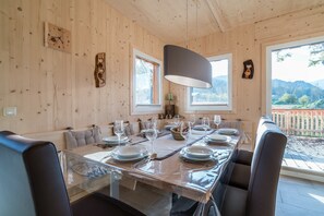 Comedor con paneles de madera, una mesa larga dispuesta para seis comensales, ventanas amplias y vistas al exterior.