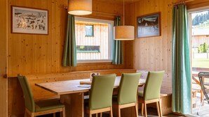 A wooden interior with a dining table and chairs, framed pictures on the walls, and a window with curtains. - Lavish Chalet in Sankt Georgen with Jacuzzi (Sankt Georgen am Kresichberg)