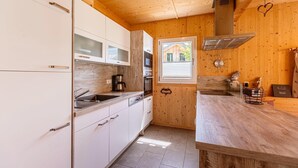 A compact kitchen with white cabinets, a wooden countertop, and a window providing natural light.