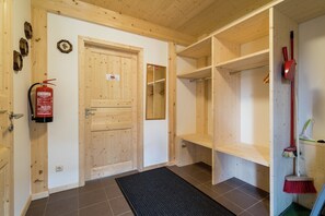 A wooden interior with a fire extinguisher, a door, and a broom leaning against the wall. - Nice chalet with whirlpool (Kreischberg Murau)