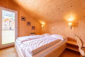 Ein Zimmer in einer Holzhütte mit zwei Betten, einem Fenster und Wandleuchten.