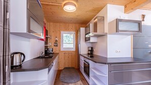 Una cocina compacta con paredes de madera, electrodomésticos de acero inoxidable y un ventanal pequeño.