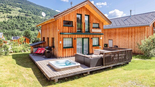 Una cabaña de madera con jacuzzi, zona de estar exterior y terraza.